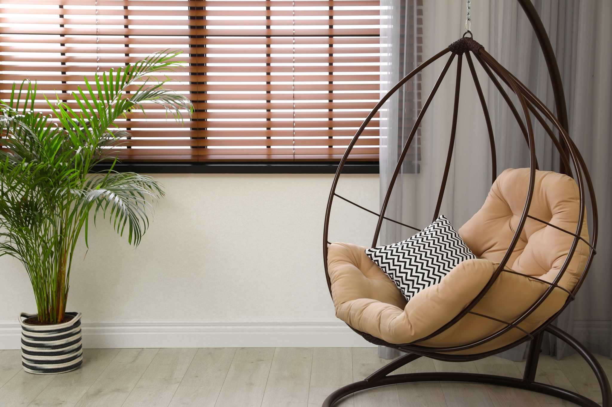Comfortable swing chair with pillows in room interior